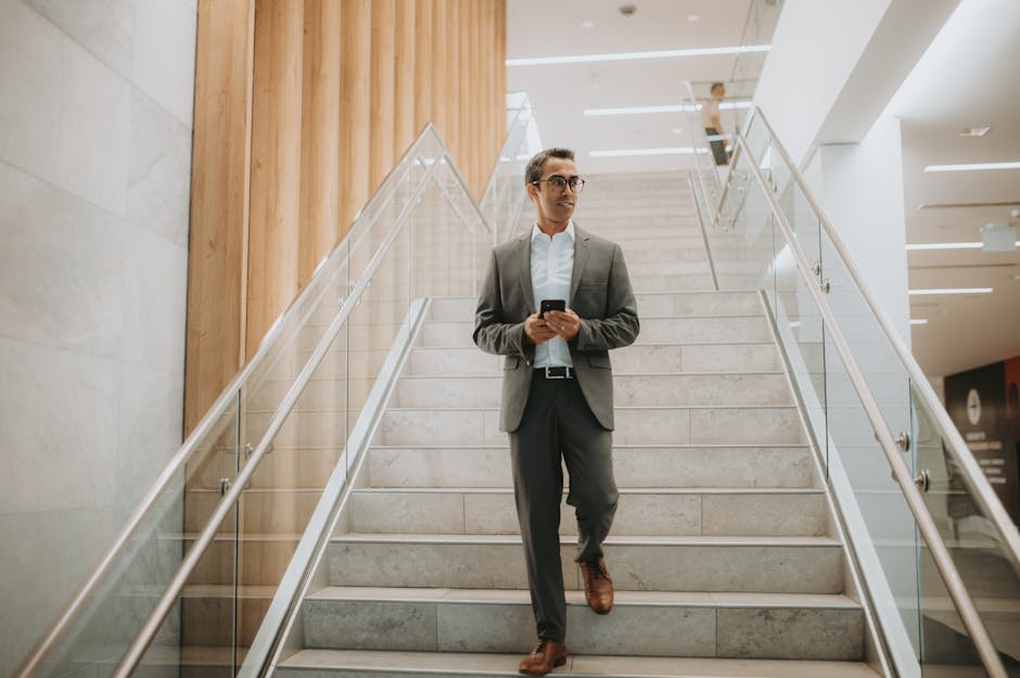 Confident businessman in suit walking downstairs while using a smartphone
