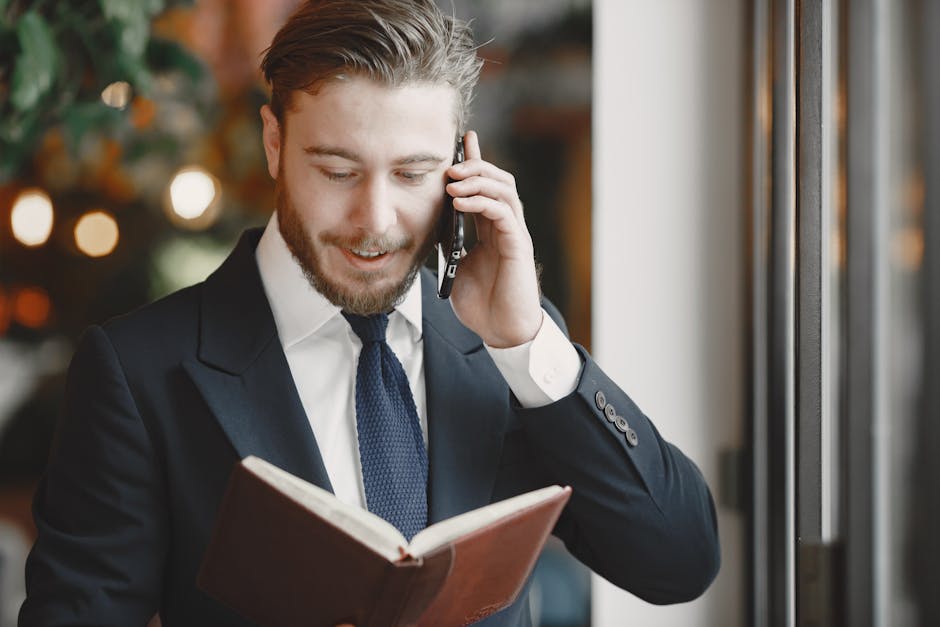 A professional businessman in a suit having a phone call while holding a book