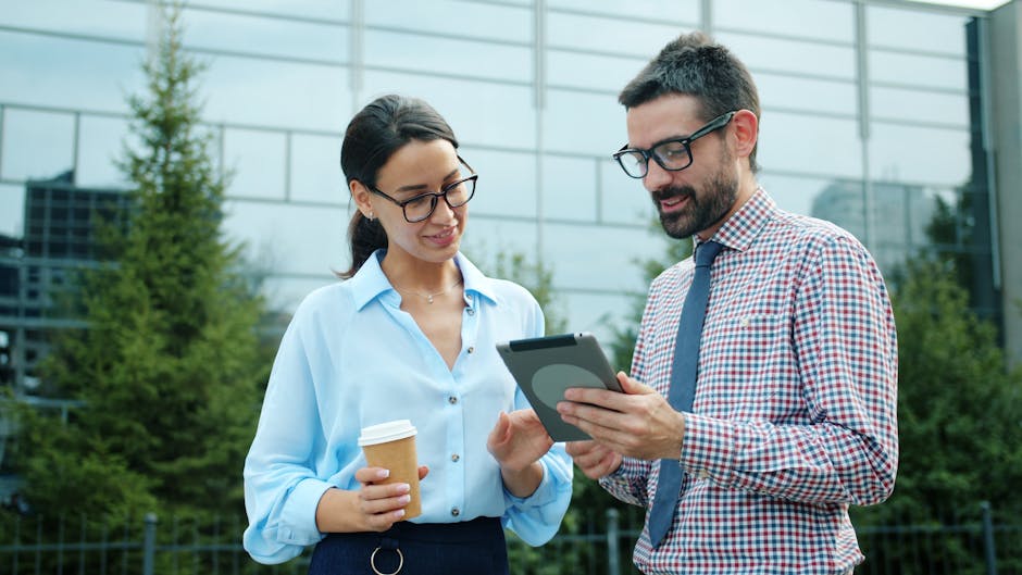 Two professionals discussing work on a tablet outdoors