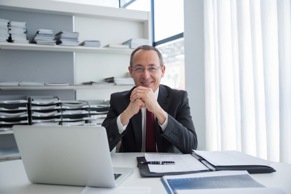 Smiling businessman in a suit with laptop and documents, exuding confidence